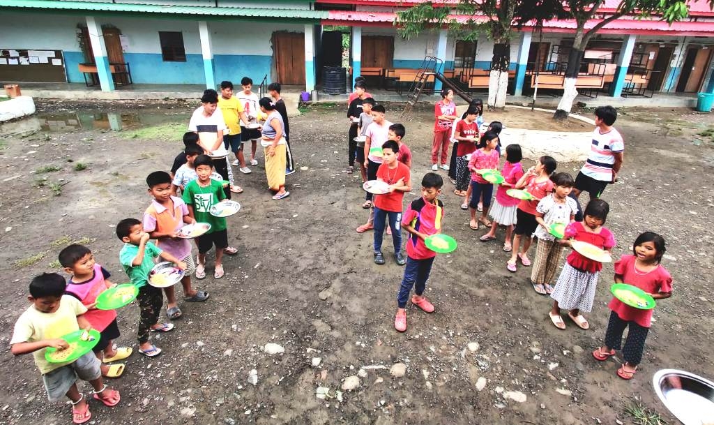 Children anxiously await their share of food as volunteers distribute meals, at the relief camp in Praja Higher Secondary School, Lamsang.